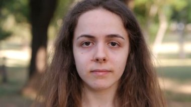 Parktaki genç kadın kameraya ve şans getiren ifadeye bakıyor.