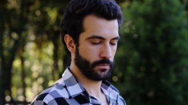 Genç endişeli bir adam başını kaldırıyor ve kameraya bakıyor.