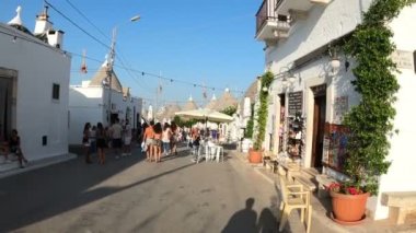 Alberobello 'nun tipik koni şekilli binaları arasında yürüyen turistler