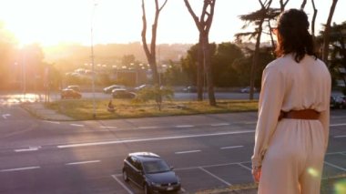 Gün batımında şehir merkezinde zarif bir kadın kolezyumun merdivenlerinden iniyor.