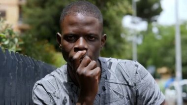 Düşünceler, endişeler genç düşünceli siyah adam kameraya bakıyor.