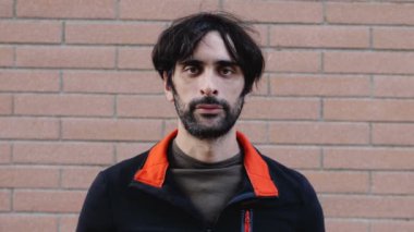 Covid 19 yaşında ciddi bir adam kameraya bakıyor ve maske takıyor.