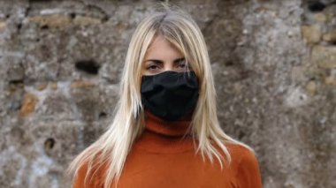 Covid 19 yaşında güzel bir kız siyah maskesini çıkarıp kameraya gülümsüyor.