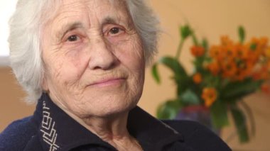 Dişsiz yaşlı kadın kameraya mutlu bir şekilde gülümsüyor.