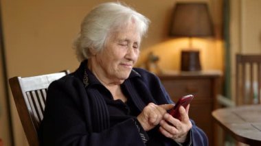 Yaşlı kadın cep telefonundan mesaj yolluyor.