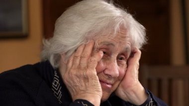 Bunalımlı yaşlı kadın, kafası ellerinin arasında düşünüyor.