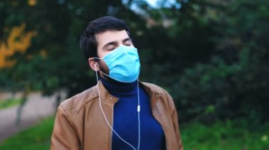 Bağlantı, teknoloji - parkta maskeli genç adam müzik dinliyor