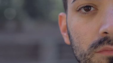 Genç ve ciddi bir adamın yarım yamalak kameraya bakarken çekilmiş portresi.