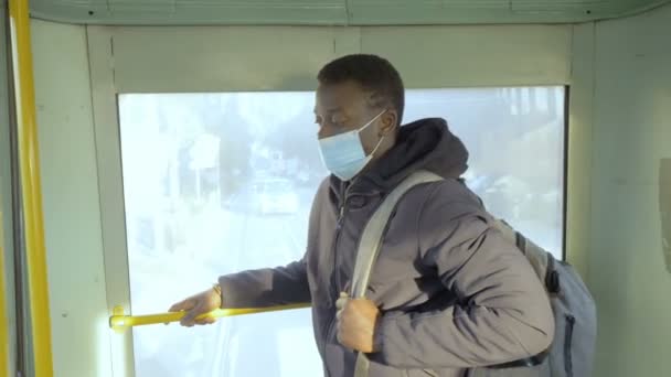 パンデミック 2021 バスに立ってマスクを持つ黒人男性は仕事から来ている — ストック動画