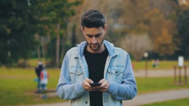 Akıllı telefon, teknoloji. Genç adam cep telefonuyla kameraya gülümsüyor. 