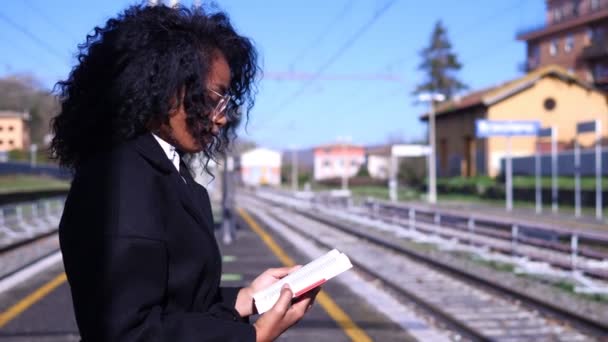 Латиноамериканка Читающая Книгу Вокзале Проверяет Едет Поезд — стоковое видео