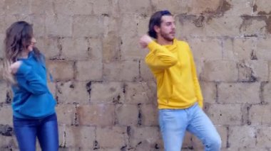 Çift, kameraya gülümseyen senkronize dans adımları çalışarak egzersiz yapıyor.