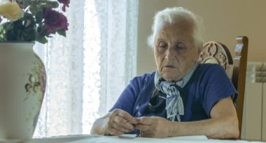 Üzgün yaşlı kadın, elinde tespih ile çapraz dua