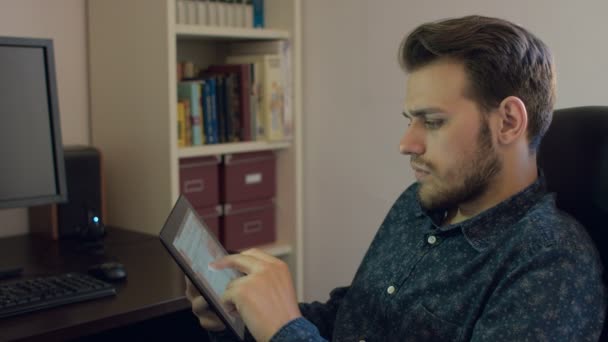 Jonge man het lezen van een Tablet PC thuis — Stockvideo