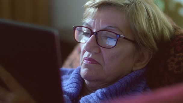 Femme âgée utilisant facebook sur la tablette pc : réflexion sur ses lunettes — Video