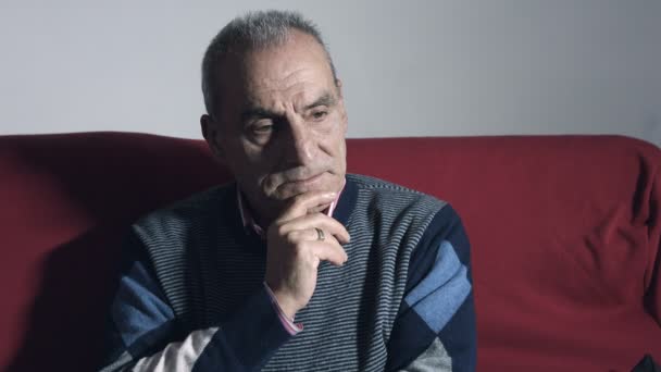 Átgondolt öreg: töprengő és komoly öreg egyedül ül a kanapén — Stock videók