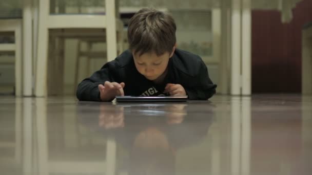 Bambino che naviga in internet con un tablet sdraiato sul pavimento — Video Stock