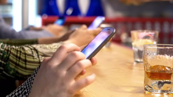 Personas que usan teléfonos inteligentes en un pub: redes sociales, teléfonos móviles, mostrador de bar — Vídeos de Stock