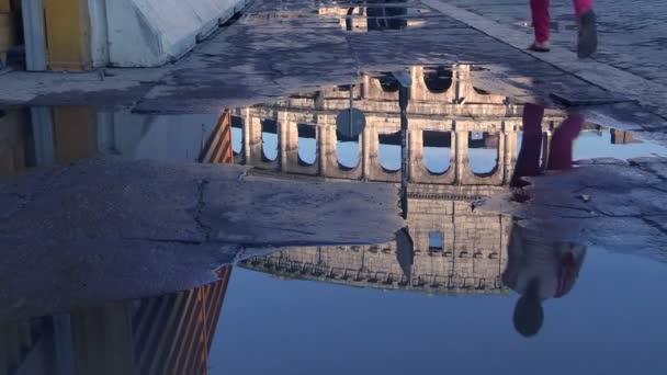 Dopo una tempesta la gente cammina riflessa su una pozzanghera davanti al coliseum — Video Stock