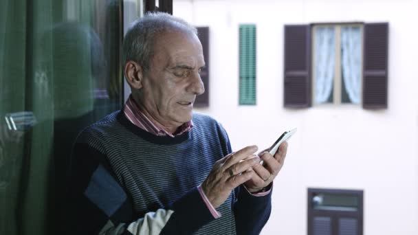 Старик пытается посмотреть видео на youtube с помощью мобильного телефона — стоковое видео