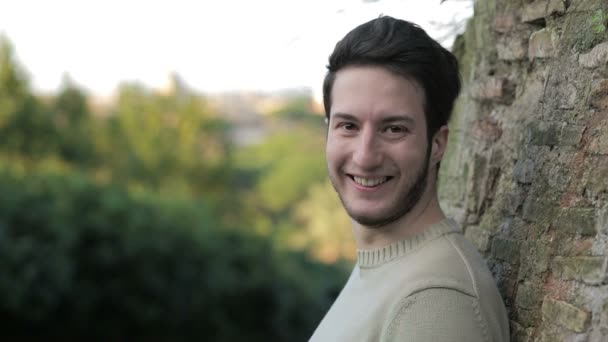 Netter junger Mann blickt in die Kamera und lächelt — Stockvideo