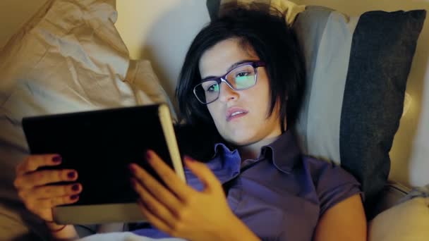 Vrouw ligt op het bed schuiven via haar tablet — Stockvideo