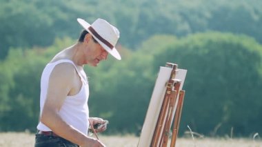 güzel bir manzara, tuval ortasında bir buğday alan ressam boyalar
