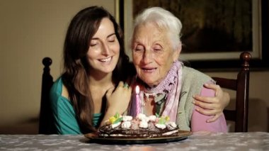 Kutluyor ve bir doğum günü pastası torunu için vererek mutlu gülümseyen büyükanne