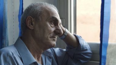 üzgün ve yalnız bir adam kötü bir şey bulutlu bir günde pencerede düşünüyor