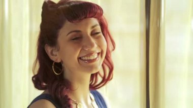 Güzel ve şirin kırmızı kız pencerenin duruyor ve kameraya doğru görünüyor