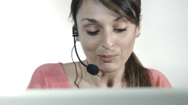 bir çağrı merkezi bilgisayar ve kulaklık ile çalışan genç kadın