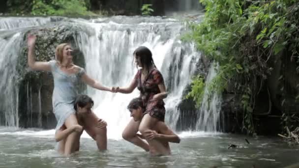 Jongens en meisjes zijn plezier in een meer, worstelen en spetteren met water — Stockvideo