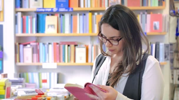 Junge schöne Frau liest in einer Buchhandlung — Stockvideo