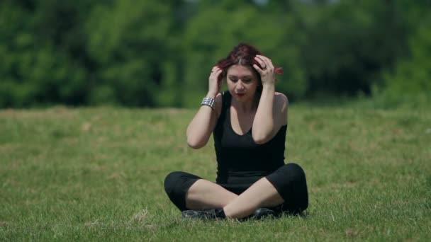 Hermosa pelirroja mujer relaja sentado en un prado, parque — Vídeo de stock
