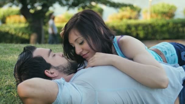 Сладкие моменты любви: молодая пара лежит на траве в парке — стоковое видео