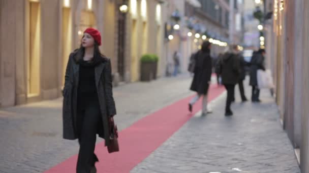 Mujer con sombrero rojo caminando en una calle — Vídeo de stock