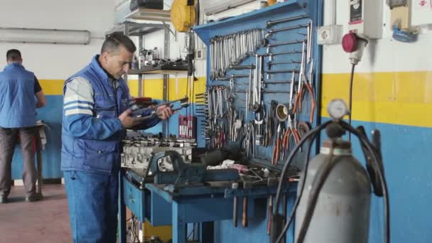 Mecánico de automóviles reparando una parte de un motor de coche — Vídeo de stock