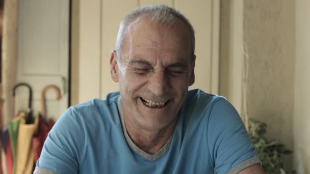 70-jarige senior oudere man buiten lachen: zitten aan de tafel, 4k, glimlachend — Stockvideo
