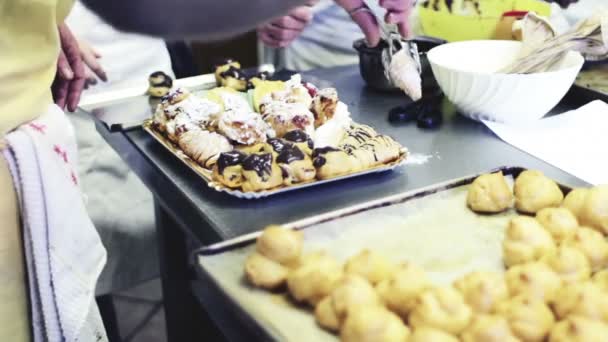 Chef van het gebakje zet gebakjes in de lade — Stockvideo