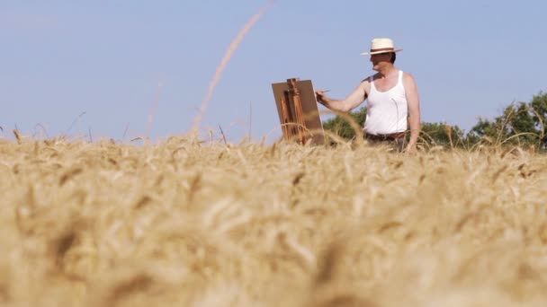 Pintor en medio de un campo de maíz pinta un hermoso paisaje, lienzo, caballete — Vídeos de Stock