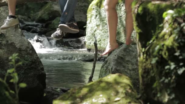 Vivir en contacto con la naturaleza - piernas colgando de un árbol cerca de un arroyo — Vídeos de Stock