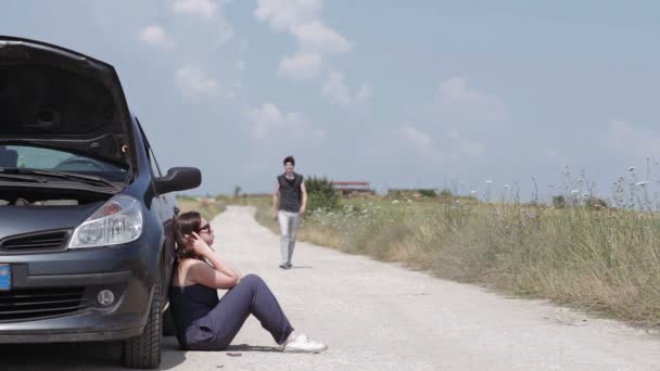 Un joven repara el coche averiado de una mujer — Vídeos de Stock