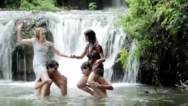 Meninos e meninas estão se divertindo em um fluxo lutando e salpicando com água — Vídeo de Stock