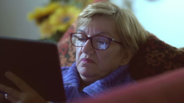 Elderly woman using tablet computer: reflection on her eyeglasses — Stock Video