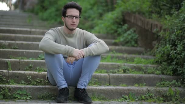 Lonely boy on staircase thinking about some problem: sad, upset, troubled — Stockvideo