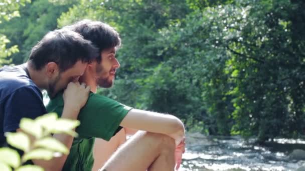 Двоє молодих чоловіків фліртують на сонці. Гей сцена з озером на фоні — стокове відео