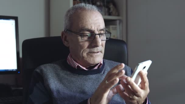 Старик сочиняет смс или чатится с современным мобильным телефоном — стоковое видео