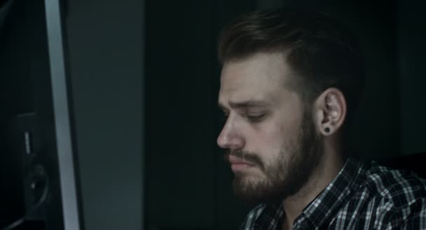 Young man using computer in the darkness: searching on the web, and chatting — Stock Video