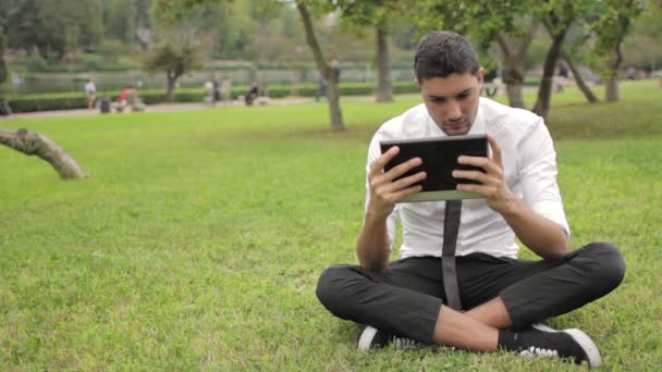 Geschäftsmann sitzt mit Tablet unterm Baum — Stockvideo