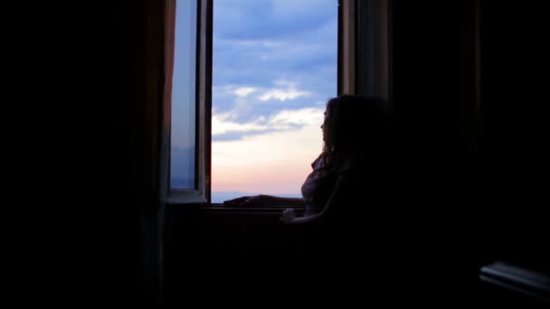 Sad and lonely woman looks out the window — Stock video